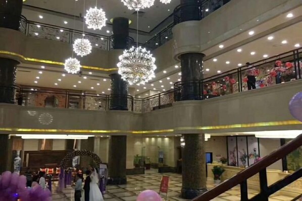 A multi-level atrium with a grand staircase, large chandeliers, and a central decorative arch.