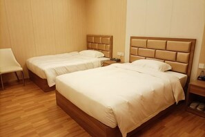 A hotel room with two beds, a wooden floor, and a chair. - Lian Shan Longshan Garden Hotel (Lianshan)