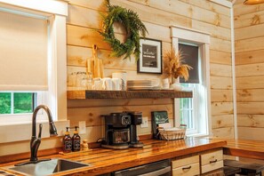 A kitchen with wooden walls, a coffee machine, and a welcome sign.