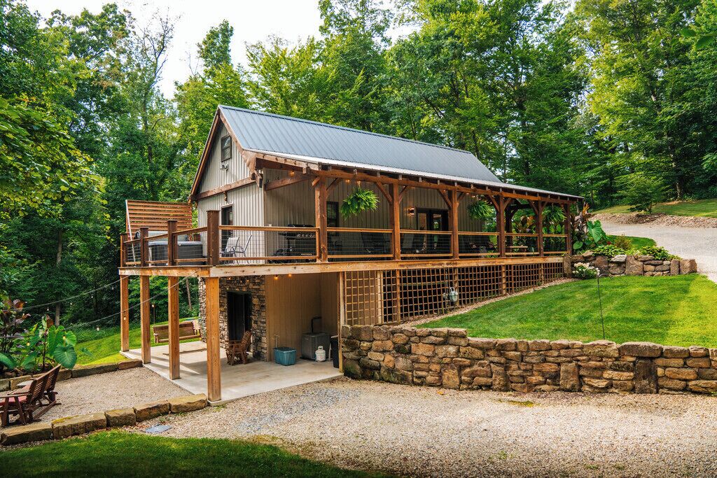 A two-story building with a covered porch and a stone wall.