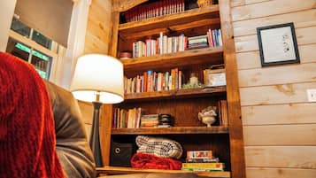 A cozy room with a leather sofa, a wooden bookshelf filled with books, and a lamp.