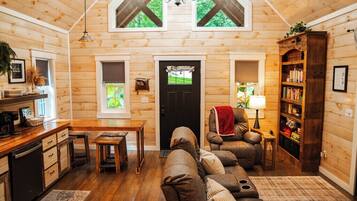 A cozy cabin interior with a wooden interior, a dining area, a sofa, and a bookshelf.