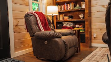 A cozy room with a leather recliner, a bookshelf, and a lamp.