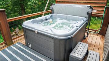 A hot tub on a wooden deck with a metal railing and a wooden fence in the background.