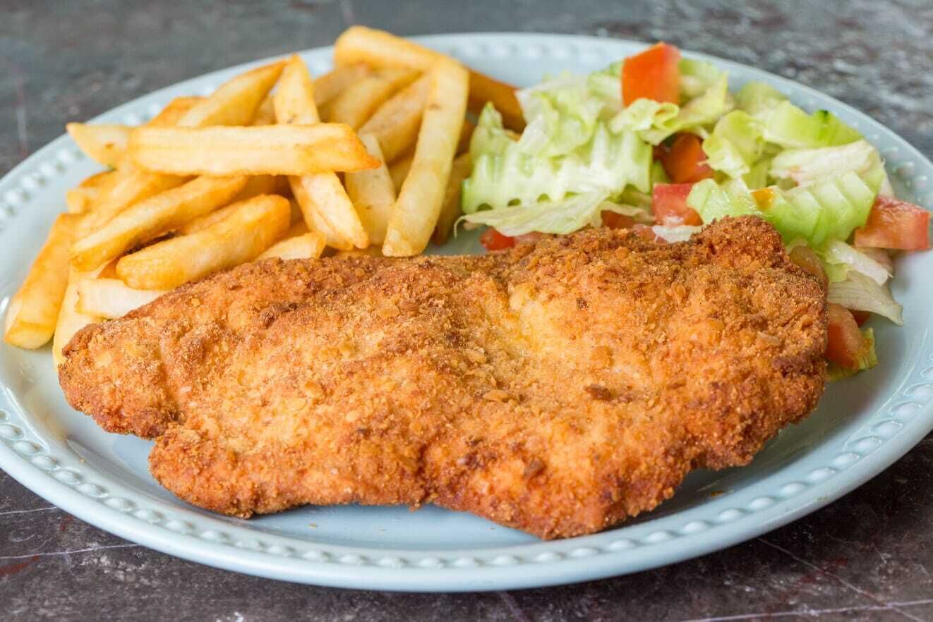 A plate with a breaded and fried cutlet, French fries, and a side salad.