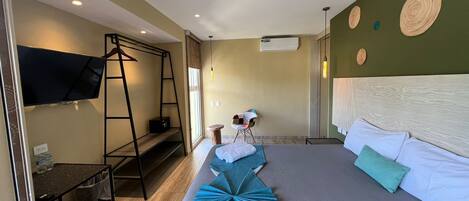 A hotel room with a bed, a TV, a desk, and a ladder.