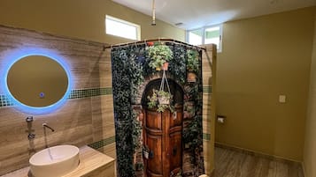 Ein Badezimmer mit einem Holzbadezimmermöbel, einem runden Spiegel und einer Duschkabine mit Türdesign.
