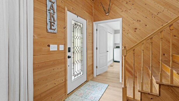 A wooden interior with a door labeled "LAKE," a staircase, and a hallway leading to another room.
