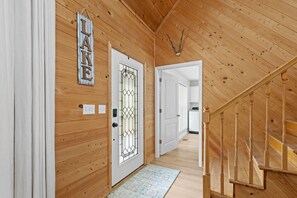 A wooden interior with a door labeled "LAKE," a staircase, and a hallway leading to another room.