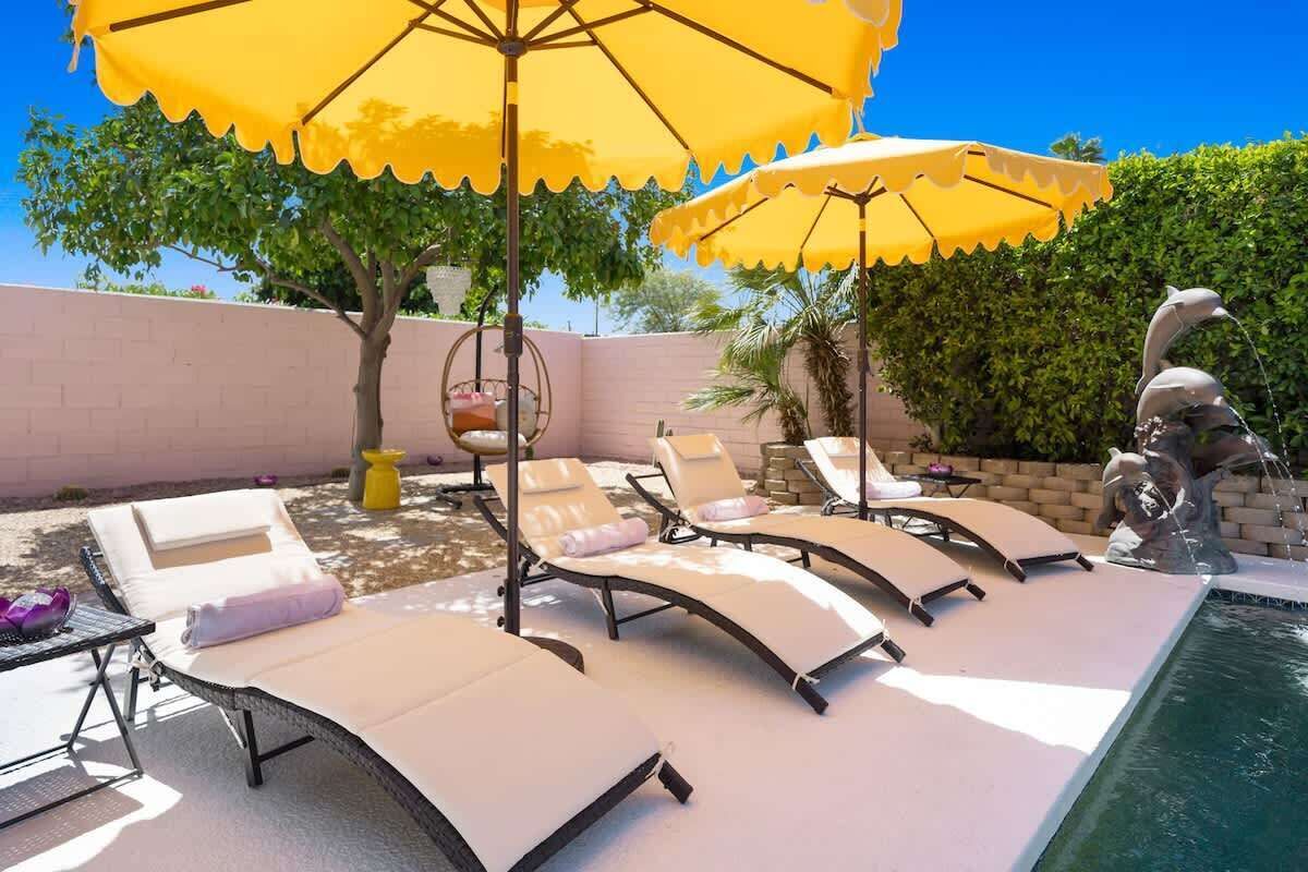 A poolside area with sun loungers, yellow umbrellas, and a decorative bird sculpture.