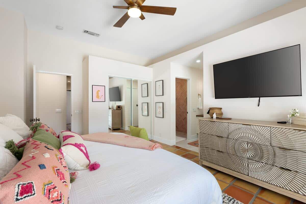 A bedroom with a bed, a TV mounted on the wall, and a decorative console table.