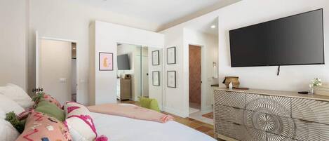 A bedroom with a bed, a TV mounted on the wall, and a decorative console table.