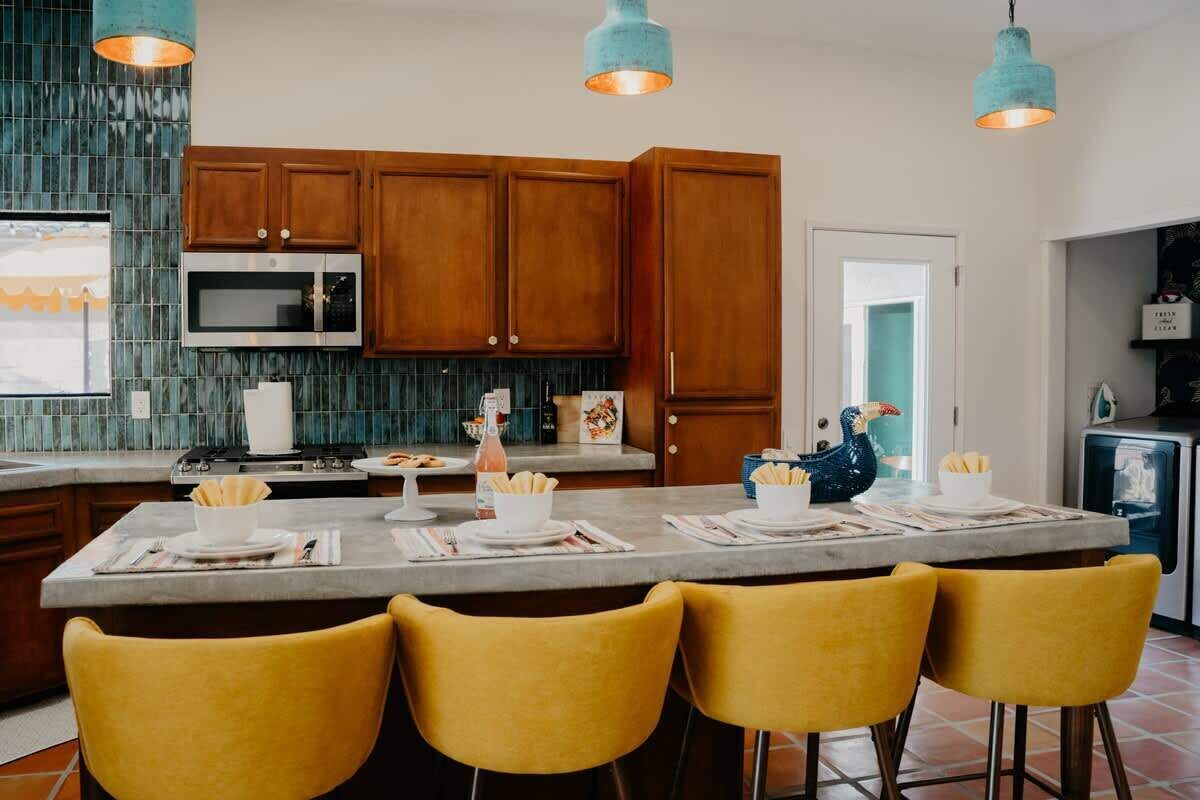 Une cuisine moderne avec des meubles en bois, un îlot central et des chaises jaunes.