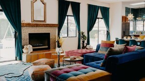 Ein Wohnzimmer mit Kamin, bunten Sofas und einem durchgehenden Durchgang zur Küche.