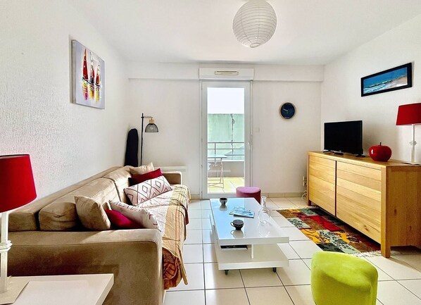 Un salon moderne avec un canapé, une table basse et un téléviseur posé sur un meuble en bois.