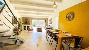 A modern interior with a dining area, staircase, and a view to the outside. - Charming villa in a quiet location with courtyard (LE BOIS PLAGE EN RE)