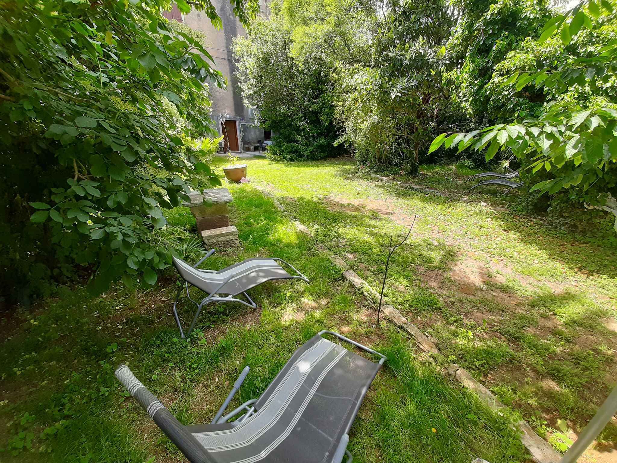 A garden with a lawn, a stone bench, and a chair.
