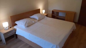 Cama bem arrumada com lençóis brancos em quarto de hotel.