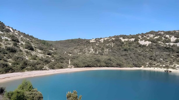 Paisagem natural com um lago azul límpido rodeado por colinas.
