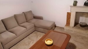 Uma sala de estar com um sofá modular bege, uma mesa de centro de madeira e uma lareira com um vaso verde e um vaso preto na mantel.