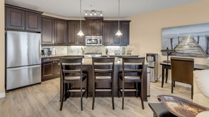A modern kitchen with dark wood cabinets, stainless steel appliances, and a central island with bar stools.