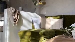 Ein grünes Sofa mit Holzbeinen, ein Holztisch und eine Vase mit Blumen.