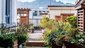 A courtyard with a wooden pergola, a small garden area, and a view of a mountain range in the background. - Yajia Hotel (Kaiyang)