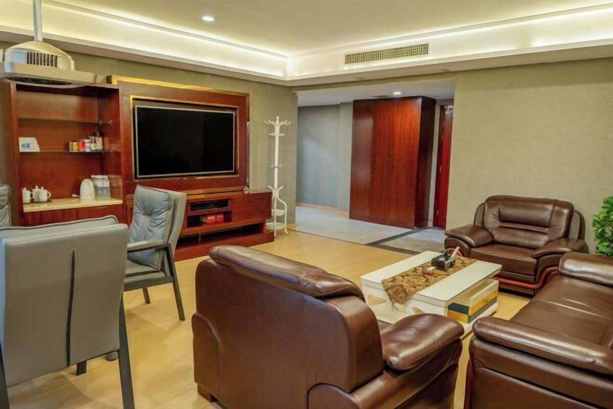 A modern living room with leather sofas, a flat-screen TV, a coffee table, and a wooden entertainment unit.