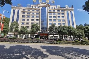 A large hotel with a central glass facade, multiple floors, and a symmetrical facade with a central entrance.
