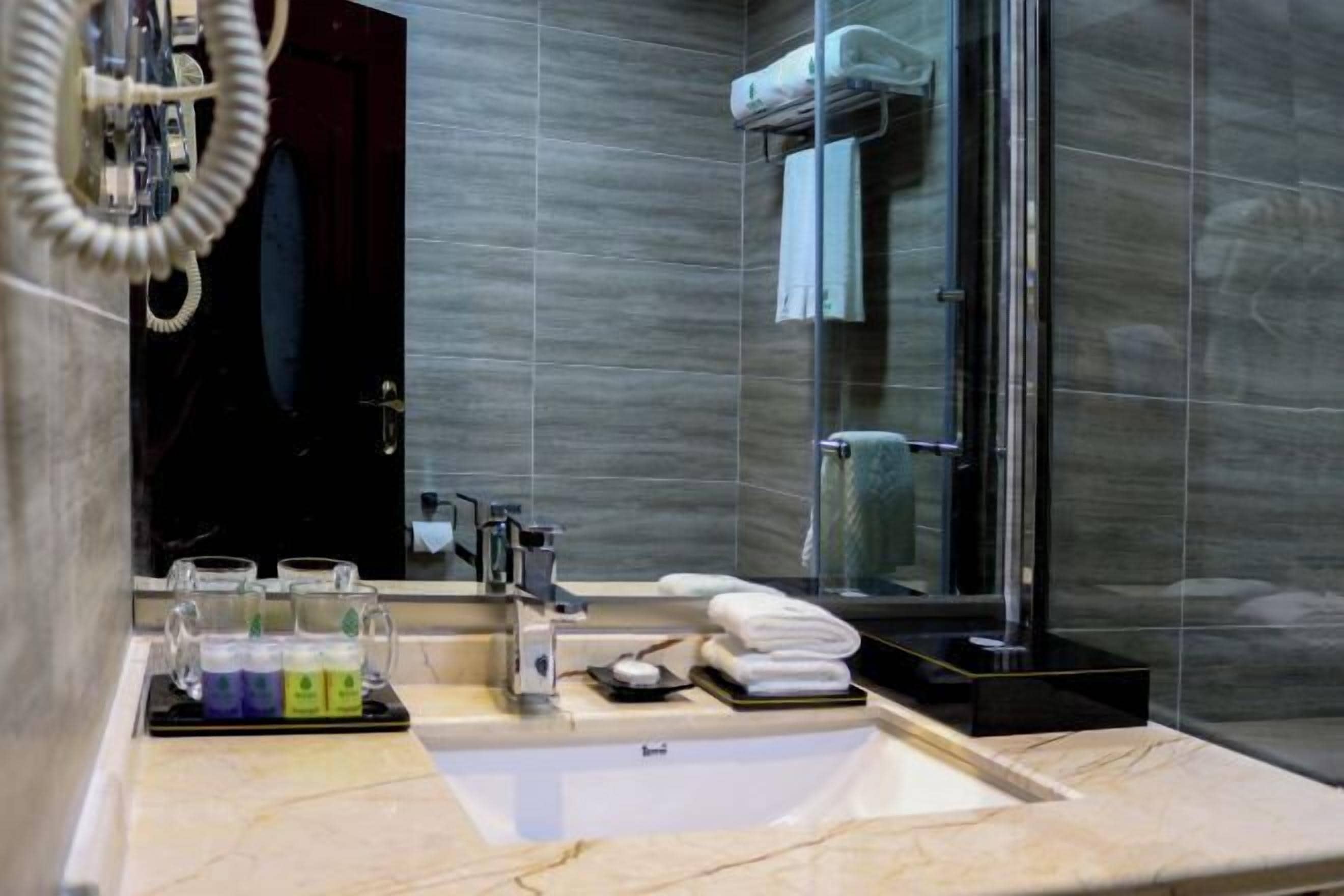 Un baño moderno con lavabo de mármol, cabina de ducha de vidrio y un perchero para toallas.