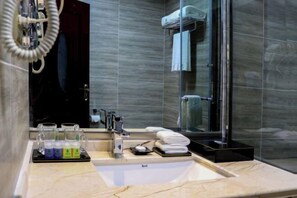 A modern bathroom with a marble sink, glass shower enclosure, and a towel rack. - Yajia Hotel (Kaiyang)