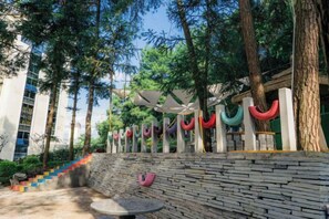 An outdoor area with a stone bench, trees, and a staircase. - Yajia Hotel (Kaiyang)