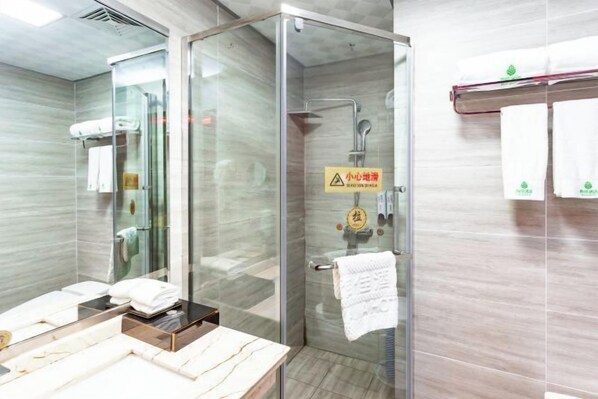 A modern bathroom with a glass shower enclosure, a vanity with a marble countertop, and a towel rack with white towels.