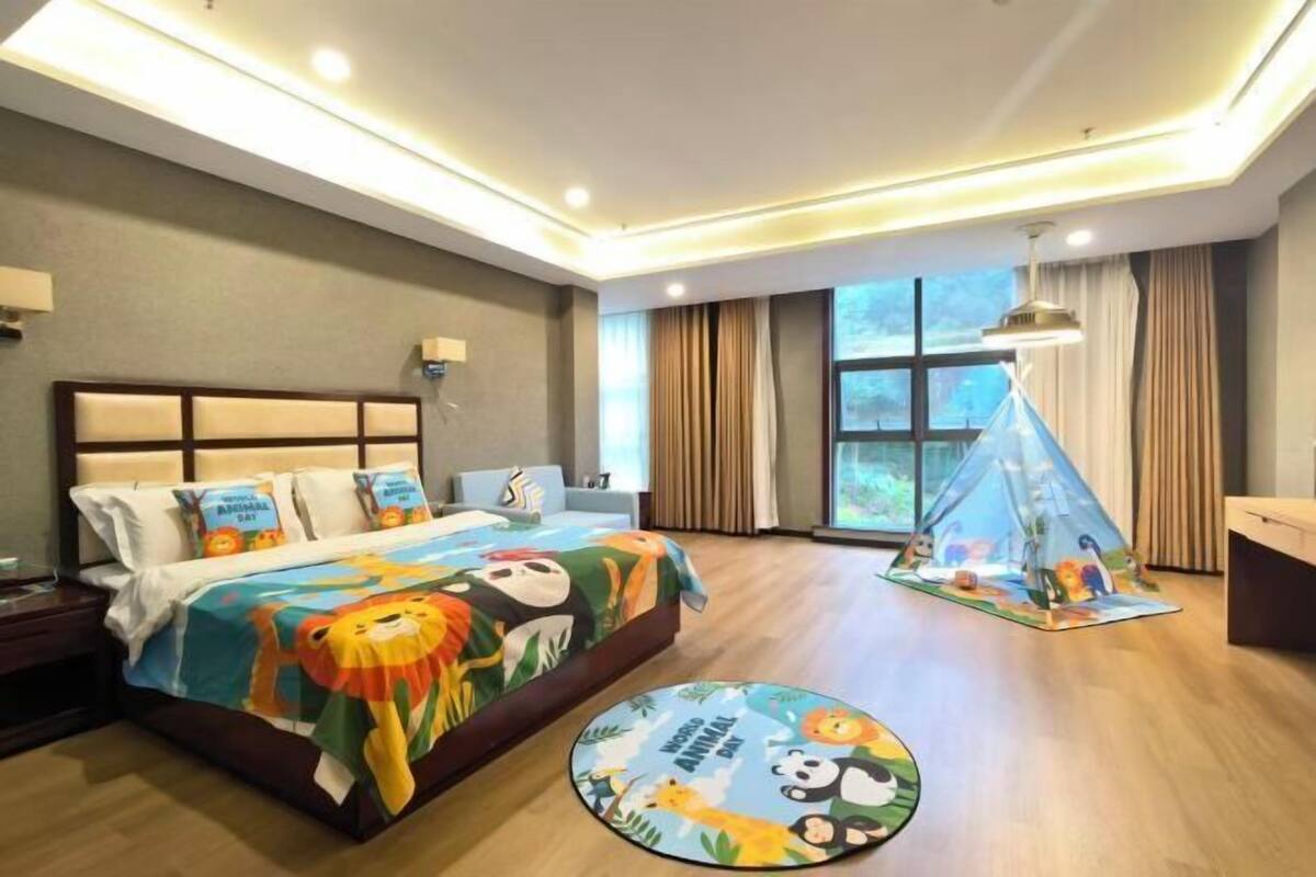 A hotel room with a bed, a nightstand, a desk, a window with curtains, and a tent decoration.
