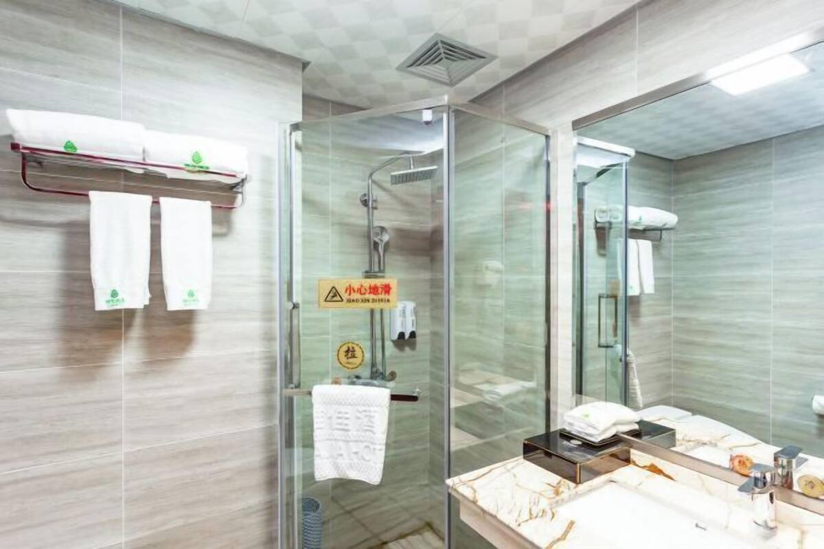 A modern bathroom with a glass-enclosed shower, a marble sink, and a towel rack with white towels.