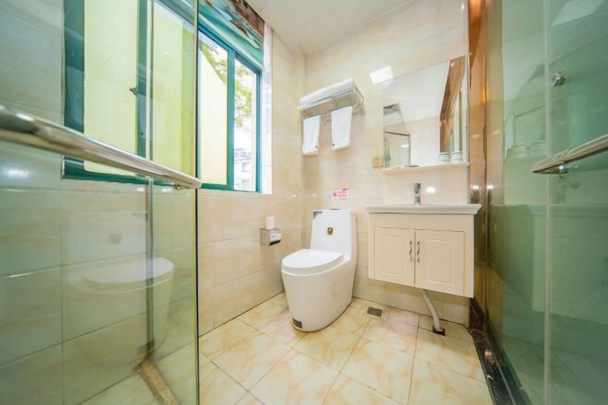 Un baño con inodoro, lavamanos, espejo y cabina de ducha de vidrio.
