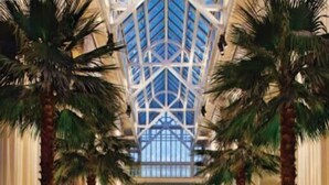 A spacious lobby with high ceilings, palm trees, and a central seating area. - La Plage Wellness (Santa Monica)