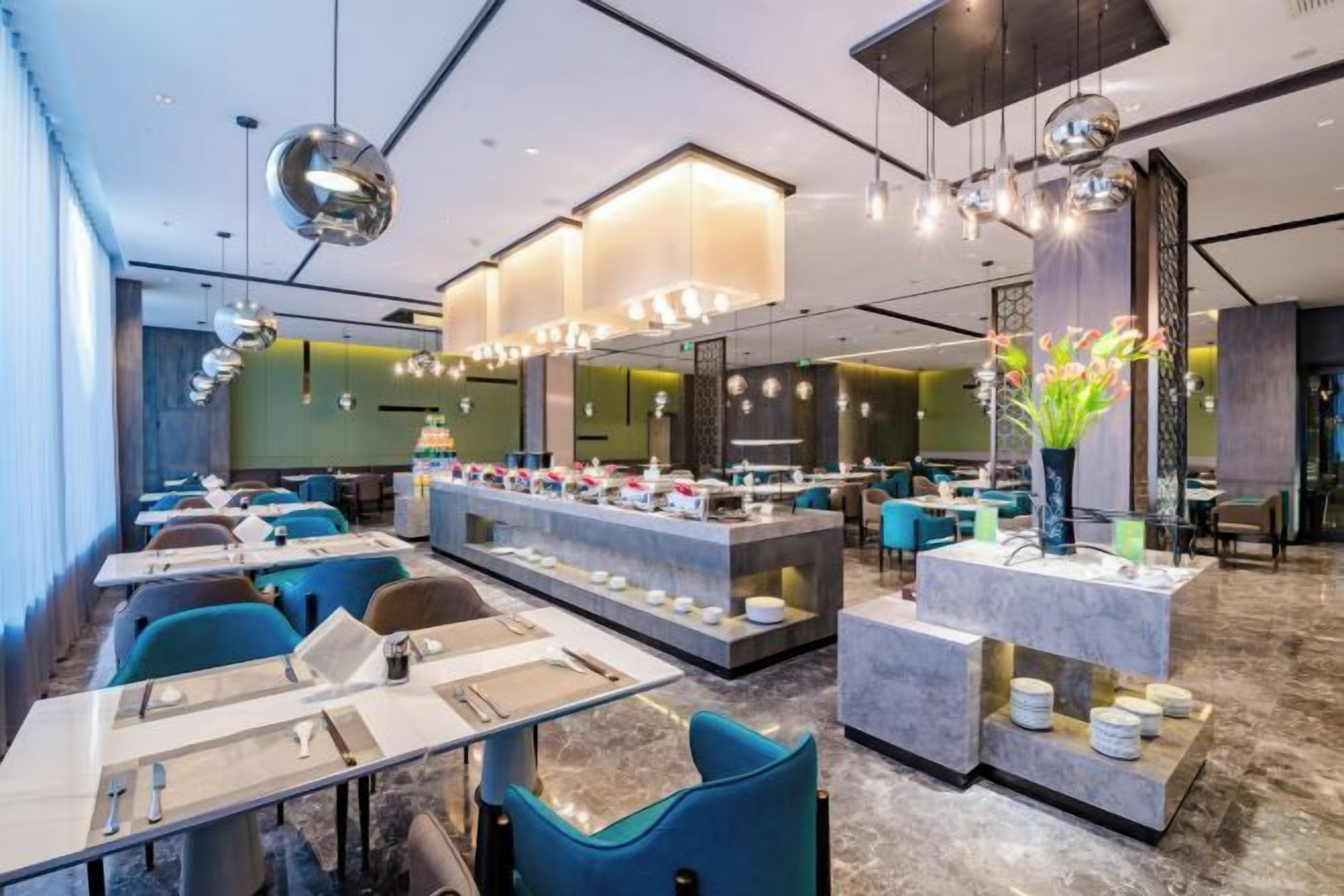 Un restaurante moderno con varias mesas, una barra central y luminarias contemporáneas.