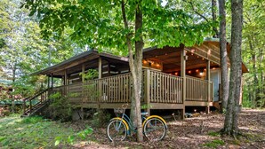 A wooden cabin with a porch and a bicycle parked in front. -  Dog Friendly w/flat lot - Between Gatlinburg and Pigeon Forge! (Sevierville)