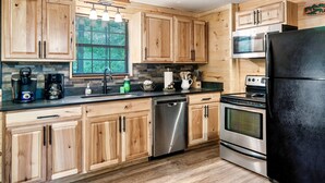 A modern kitchen with wooden cabinets, stainless steel appliances, and a black refrigerator. -  Dog Friendly w/flat lot - Between Gatlinburg and Pigeon Forge! (Sevierville)