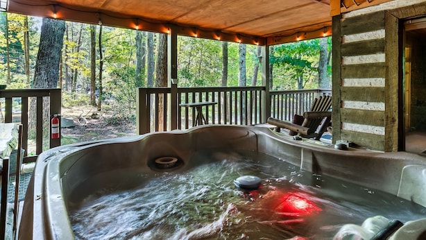 A hot tub with a wooden deck and railing, surrounded by trees. -  Dog Friendly w/flat lot - Between Gatlinburg and Pigeon Forge! (Sevierville)