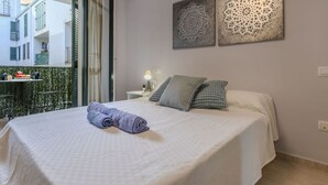 A hotel room with a bed, a nightstand, a lamp, and two wall art pieces. - Apartment Mitsu by Interhome (Tossa de Mar)