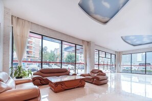 A spacious hotel lobby with leather sofas, a coffee table, and large windows offering views of the outside. - Yake Hotel (Jingxi)