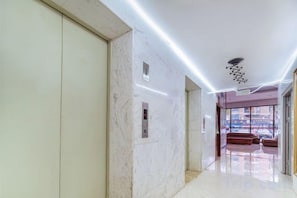 A modern interior with a marble floor, a ceiling light fixture, and a view through a glass door. - Yake Hotel (Jingxi)