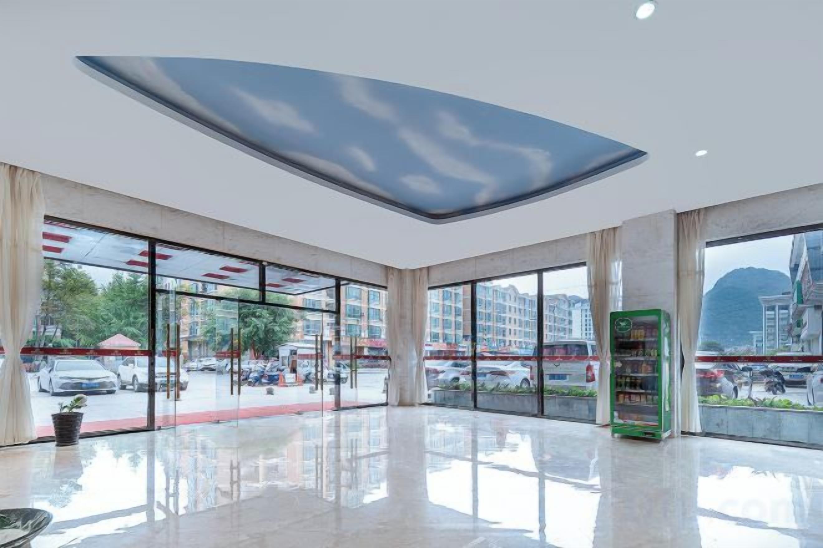 A spacious lobby with large windows, a vending machine, and a ceiling with a cloud design.