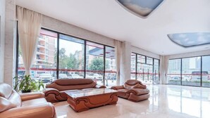 Un vestíbulo amplio con sofás de cuero, una mesa de centro y ventanas grandes con vistas al estacionamiento exterior.