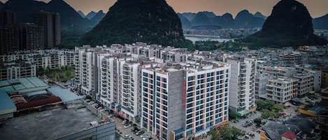 Un edificio de gran altura con varios pisos, rodeado por un paisaje urbano y montañas al fondo.