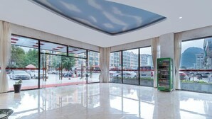 Un vestíbulo amplio con ventanas grandes, una máquina expendedora verde y un diseño de techo moderno.