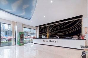 A reception area with a modern design, a reception desk, and a vending machine. - Yake Hotel (Jingxi)
