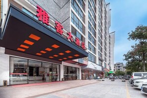 A hotel with a modern facade, large windows, and a prominent entrance with a red awning. - Yake Hotel (Jingxi)